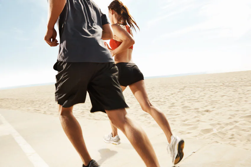 Two people running on a sandy beach